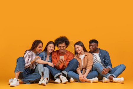 Eine multiethnische Gruppe von Freunden verbindet sich über ein Smartphone und reflektiert Verbindung und Technologie in einem multirassischen Szenario, isoliert auf gelbem Hintergrund