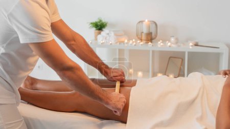 Foto de Un ambiente sereno de sala de masajes con una masajista profesional que proporciona un relajante masaje de espalda a un cliente cubierto con una toalla. El ambiente sugiere tranquilidad y lujo - Imagen libre de derechos