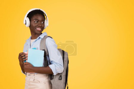 Deep in thought, this African American woman student represents the reflective attitude of Gen Z while holding her notebooks Isolated against a yellow background, copy space