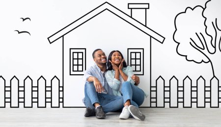 Photo for Cute black family husband and wife sitting over drawn on white wall house, embracing and smiling. Real estate, mortgage concept - Royalty Free Image