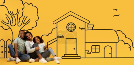 Heureuse famille afro-américaine de trois père mère et fille assis sur le sol et regardant la maison illustrée de leurs rêves sur fond de mur jaune