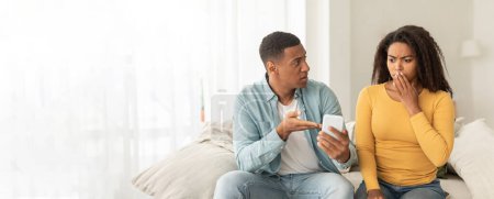 Foto de Una pareja afroamericana que se involucra con un teléfono inteligente que muestra preocupación o confusión, con suficiente espacio de copia para un banner web - Imagen libre de derechos