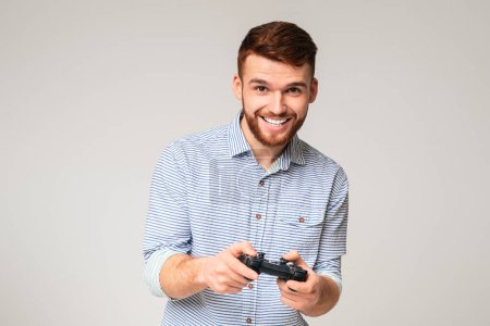 Photo for Excited millennial guy playing video games with jpystick and smiling, panorama, free space - Royalty Free Image