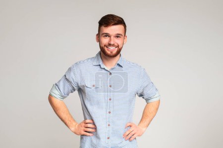 Porträt eines lächelnden Typen mit Händen auf Hüften auf beigem Hintergrund, Panorama, Kopierraum