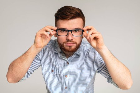 Photo for Young redhaired guy try on glasses in front of camera on studio background, panorama - Royalty Free Image