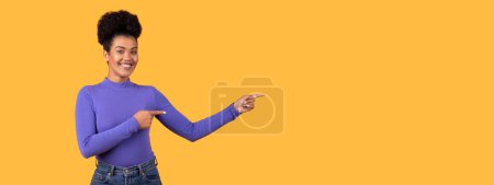 Photo for A woman wearing a purple shirt is visibly pointing at copy space. The gesture indicates her focus or interest in whatever she is pointing towards, web-banner - Royalty Free Image