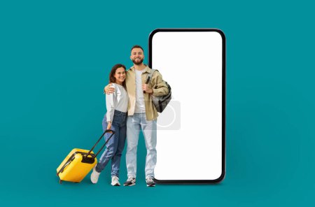Téléchargez les photos : Un couple souriant se tient à côté d'un smartphone surdimensionné avec un écran vierge, représentant le voyage et la technologie dans un concept numérique isolé - en image libre de droit