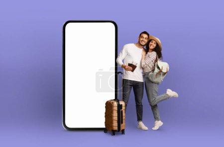 Foto de Pareja cariñosa apoyada la una en la otra por un enorme smartphone con pantalla en blanco, mostrando tecnología digital para viajar - Imagen libre de derechos