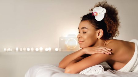 An African American woman enjoys a serene moment at a spa, with a focus on relaxation and well-being, showcasing a tranquil spa environment