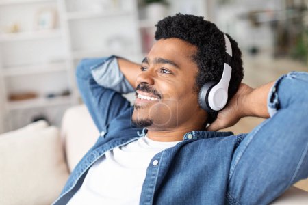 Téléchargez les photos : Capturant un moment de joie, un Afro-Américain se livre à la musique à la maison, portant des écouteurs pour une expérience intime avec ses mélodies préférées - en image libre de droit