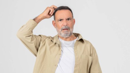 Photo for A senior man with a beard wearing a white shirt is standing in a simple and understated pose. His facial hair is neatly trimmed, and his shirt is crisp and clean, touching his head - Royalty Free Image