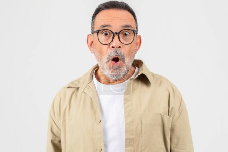 Photo for A senior man with a surprised expression on his face, his eyes wide open and mouth slightly agape. He appears shocked or amazed by something he seeing or hearing. - Royalty Free Image