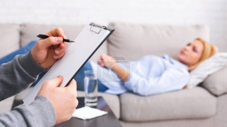 Photo for Mental health and counseling concept. Psychologist listening to depressed female patient and writing down notes, panorama - Royalty Free Image