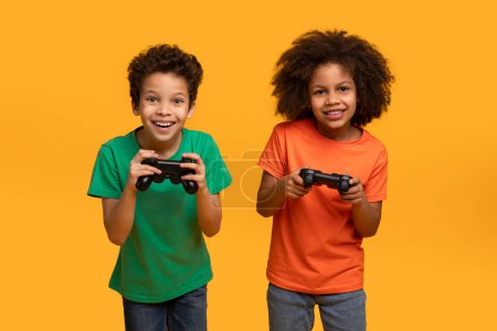 Photo for Two African American boys, both holding video game controllers in their hands, seem engrossed in an intense gaming session. Their faces show concentration and excitement as they focus on the screen. - Royalty Free Image