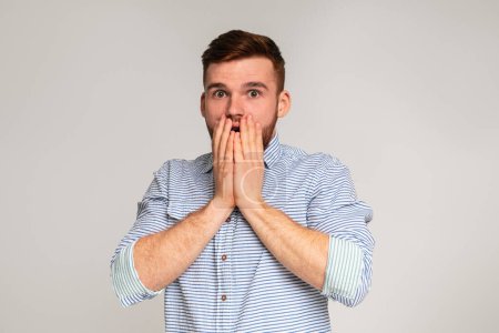 Photo for Surprised guy. Shocked man holding his hends hiding open mouth on studio background, panorama, copy space - Royalty Free Image