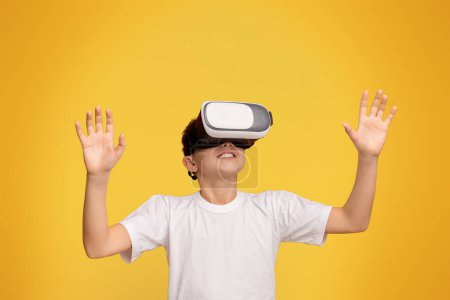 Foto de Realidad aumentada en casa. Adolescente niño disfrutando de la tecnología 3D en auriculares de realidad virtual, fondo panorama naranja - Imagen libre de derechos