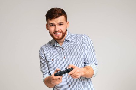 Photo for Gambling addiction. Young guy holding joystick and playing video games on studio background, panorama, copy space - Royalty Free Image