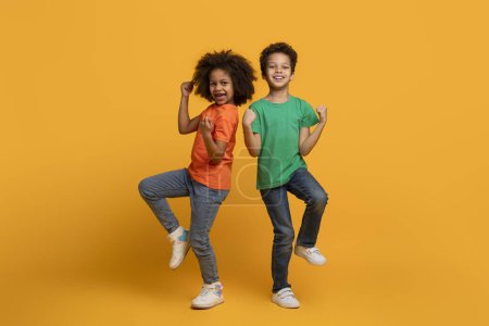 Photo for Two African American children, both young and full of energy, are captured mid-air as they jump together. Their bodies are lifted off the ground, displaying pure joy and excitement in their faces. - Royalty Free Image