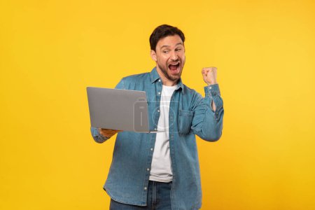 Photo for A man is joyfully celebrating while holding a laptop in his hands. He is likely reacting to good news or completing a successful task on the device. - Royalty Free Image
