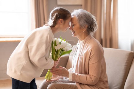 Téléchargez les photos : An elderly woman is handing a colorful bouquet of flowers to a young girl, who looks delighted and thankful. The scene captures a heartwarming moment of intergenerational kindness. - en image libre de droit
