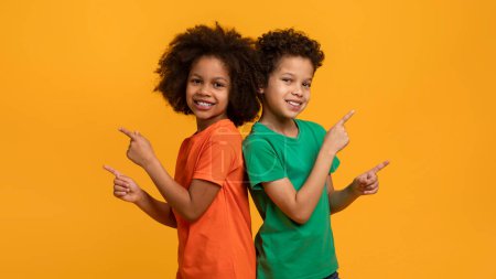 Téléchargez les photos : Afro-américains deux jeunes enfants se tiennent côte à côte. Ils ont tous deux une posture décontractée, regardant droit devant eux. Le garçon porte une chemise bleue tandis que la fille est dans une robe rose. - en image libre de droit