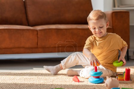 A young boy is engrossed in playing with various toys on the floor of a room. He is surrounded by different toys, including cars, blocks, and action figures