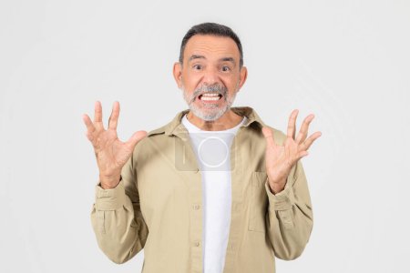 Ein älterer Mann, beide Hände in die Luft gereckt, sein Gesichtsausdruck überrascht. Sein Mund ist leicht geöffnet, und seine Augenbrauen sind hochgezogen. Er wirkt schockiert oder erschrocken.