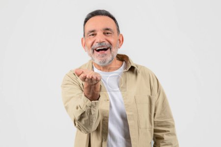 Photo for A senior man wearing a tan jacket is contorting his face into a funny expression, possibly for comedic effect or entertainment. He appears to be in a lighthearted and playful mood. - Royalty Free Image
