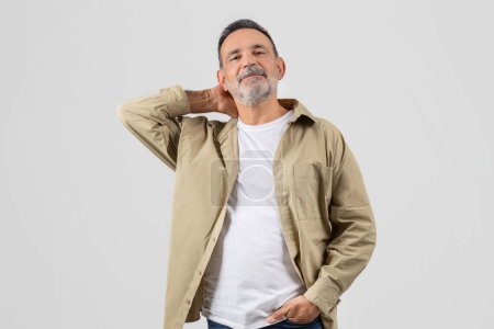 Photo for A senior man with a full beard wearing a crisp white shirt stands confidently. His facial hair is neatly trimmed, emphasizing his rugged features. He exudes a sense of masculinity and strength. - Royalty Free Image