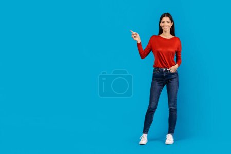 A woman wearing a red shirt is standing and pointing towards an unspecified object or direction. She appears to be gesturing with a sense of urgency or importance, copy space