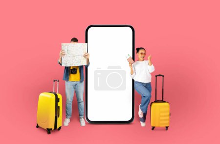 Téléchargez les photos : Voyageurs homme couvrant leur visage avec une carte et une femme avec passeport et téléphone portable à côté d'une maquette de téléphone sur un fond rose - en image libre de droit