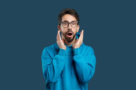 Photo for A man wearing glasses with a surprised expression on his face. His eyes widen, eyebrows raise, and mouth forms an O shape in astonishment. The man appears shocked or startled by something unexpected. - Royalty Free Image