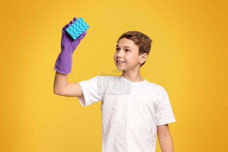 Photo for A young boy is holding up a blue sponge in his hand. - Royalty Free Image