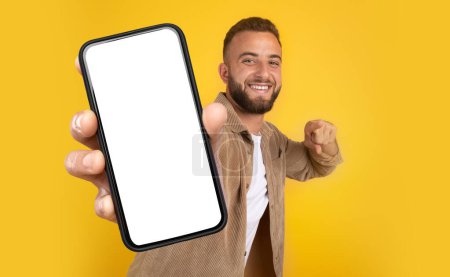 Foto de Un hombre sostiene un teléfono celular en su mano, mostrando una expresión enfocada. Su mano agarra el teléfono firmemente mientras mira atentamente a la pantalla, espacio de copia maqueta - Imagen libre de derechos