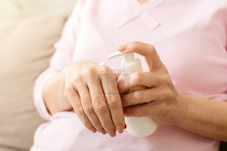 Pflege der alten Haut. Hände Seniorin Anwendung feuchtigkeitsspendende Creme, Nahaufnahme