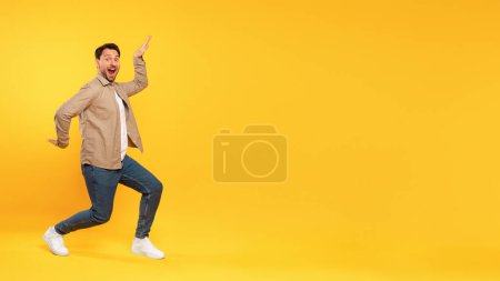A man wearing a tan jacket is energetically dancing. He is moving to the rhythm, showcasing fluid dance moves, enjoys the music, expressing joy through his movements, copy space