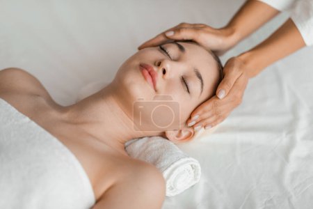 A young blonde woman enjoys a relaxing facial massage at a spa, embodying serenity and tranquility in a soothing environment
