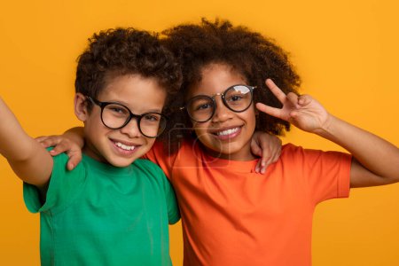 Téléchargez les photos : Deux jeunes afro-américains, tous deux portant des lunettes, se tiennent ensemble et prennent une pose pour une photo. Ils sourient et regardent directement la caméra - en image libre de droit