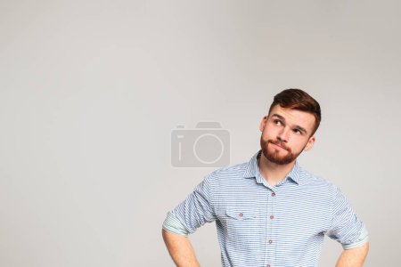 Thoughtful man looking away at copy space on studio background, panorama