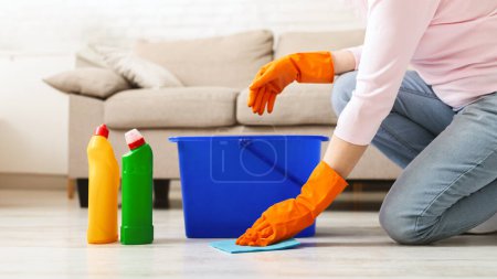 Téléchargez les photos : Femme avec trouble obsessionnel compulsif nettoyage sol avec des détergents à la maison, espace vide - en image libre de droit