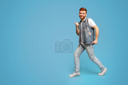 Photo for Cool millennial man dancing with thumbs up gestures on blue background, studio, copy space - Royalty Free Image