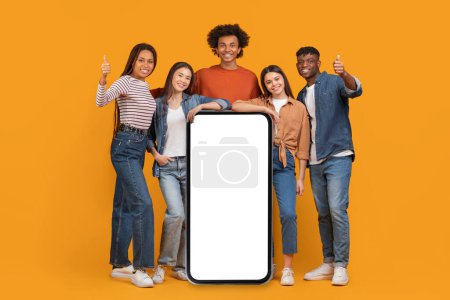 An international team of friends surrounds a large blank smartphone screen, depicting a concept of a connected, multiethnic, and multiracial team isolated on orange
