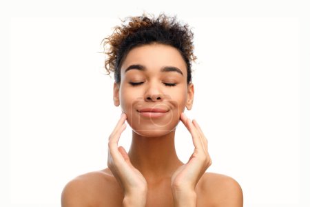 Photo for Calm african american woman with eyes closed touching her face gently, suggesting tranquility, spa themes, and a strong connection with body care - Royalty Free Image