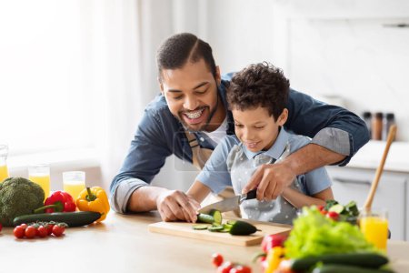 Photo for Joyful African American father and son duo engaged in cooking healthy food in the kitchen, highlighting bonding and African American culture - Royalty Free Image