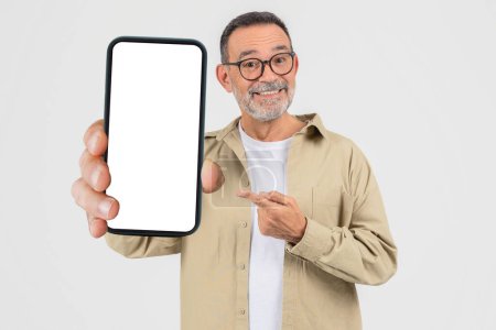 An elderly man confidently shows a blank smartphone screen, pointing to it suggesting importance or new content, isolated on a white background