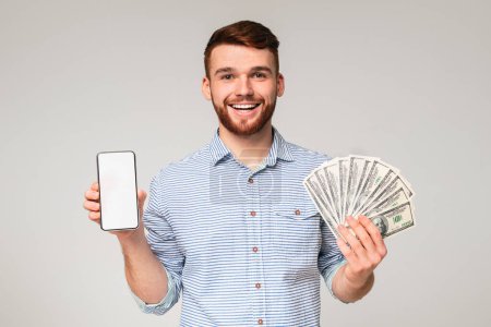 Freelance work. Handsome guy with cellphone and fan of dollars on beige background, panorama