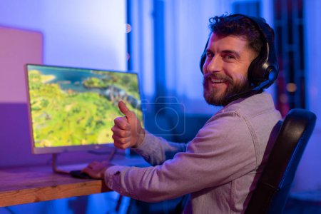 Content millennial guy with a smile, enjoying his time gameplaying. Represents casual home gaming, potentially reflecting gaming addiction issues