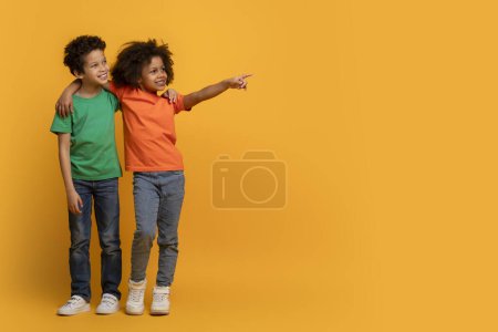 Foto de Los niños afroamericanos se paran uno al lado del otro contra un fondo amarillo vivo. Sus expresiones felices y la pose dinámica transmiten un sentido de amistad y curiosidad, espacio de copia - Imagen libre de derechos