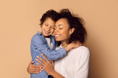 Téléchargez les photos : Femme afro-américaine tenant un enfant dans ses bras, montrant des soins maternels et de l'affection dans un moment réconfortant. - en image libre de droit