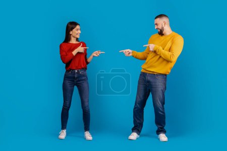 Un homme et une femme debout face à face, tous deux se pointant du doigt avec des expressions sérieuses. Ils semblent être engagés dans une discussion ou un débat animé.